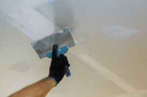 Builder repairs wall with a spatula plaster