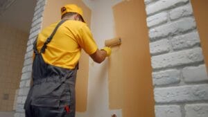 Worker painting wall with paint roller