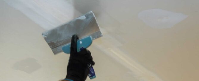 Builder repairs wall with a spatula plaster